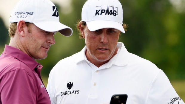 Phil Mickelson and Brandt Snedeker check the weather on a cell phone.